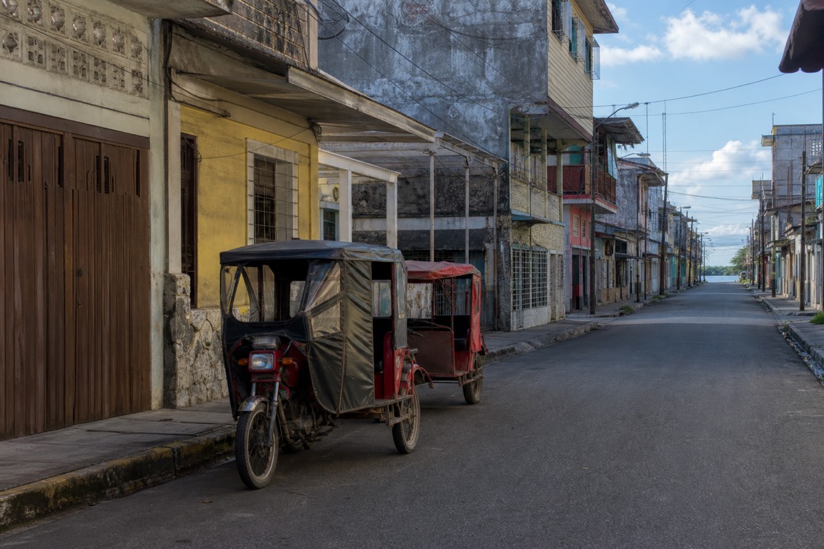 Busy street in Iquitos Peru filled with motorcarts under low tropical buildings